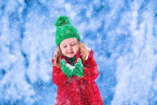 Little girl playing in snowy winter park